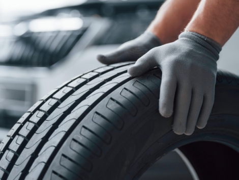 hands-only-mechanic-holding-a-tire-at-the-repair-garage-replacement-of-winter-and-summer-tires-scaled-1100x619